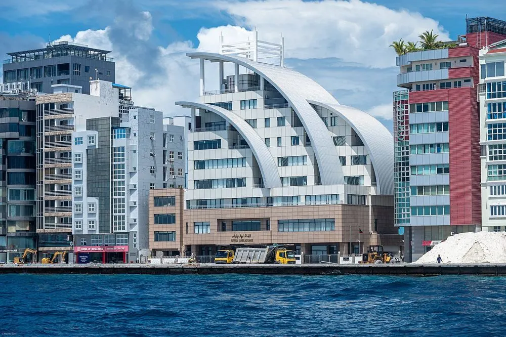 Malé's waterfront seen from the sea, with a white building with curved roofs